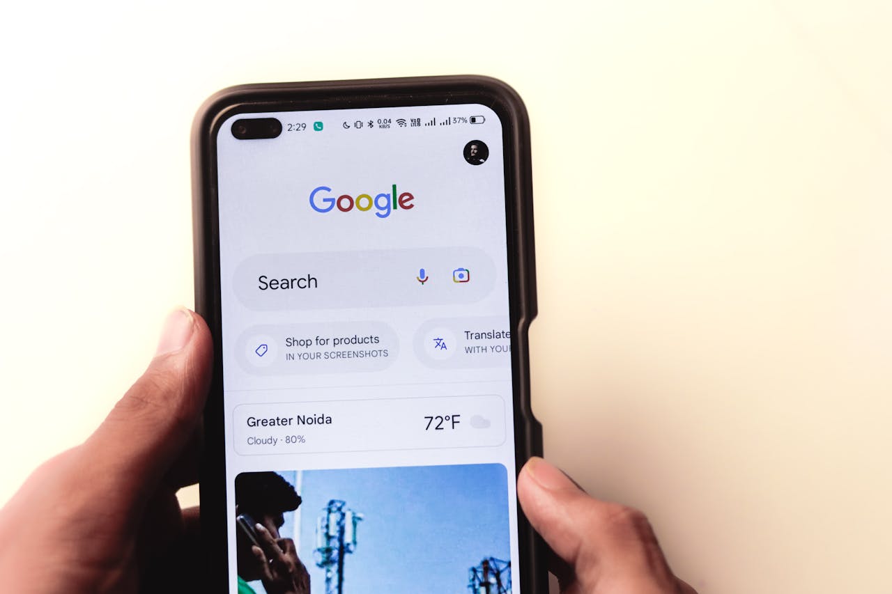hero-img A close-up of a hand holding a smartphone with Google search displayed on the screen.